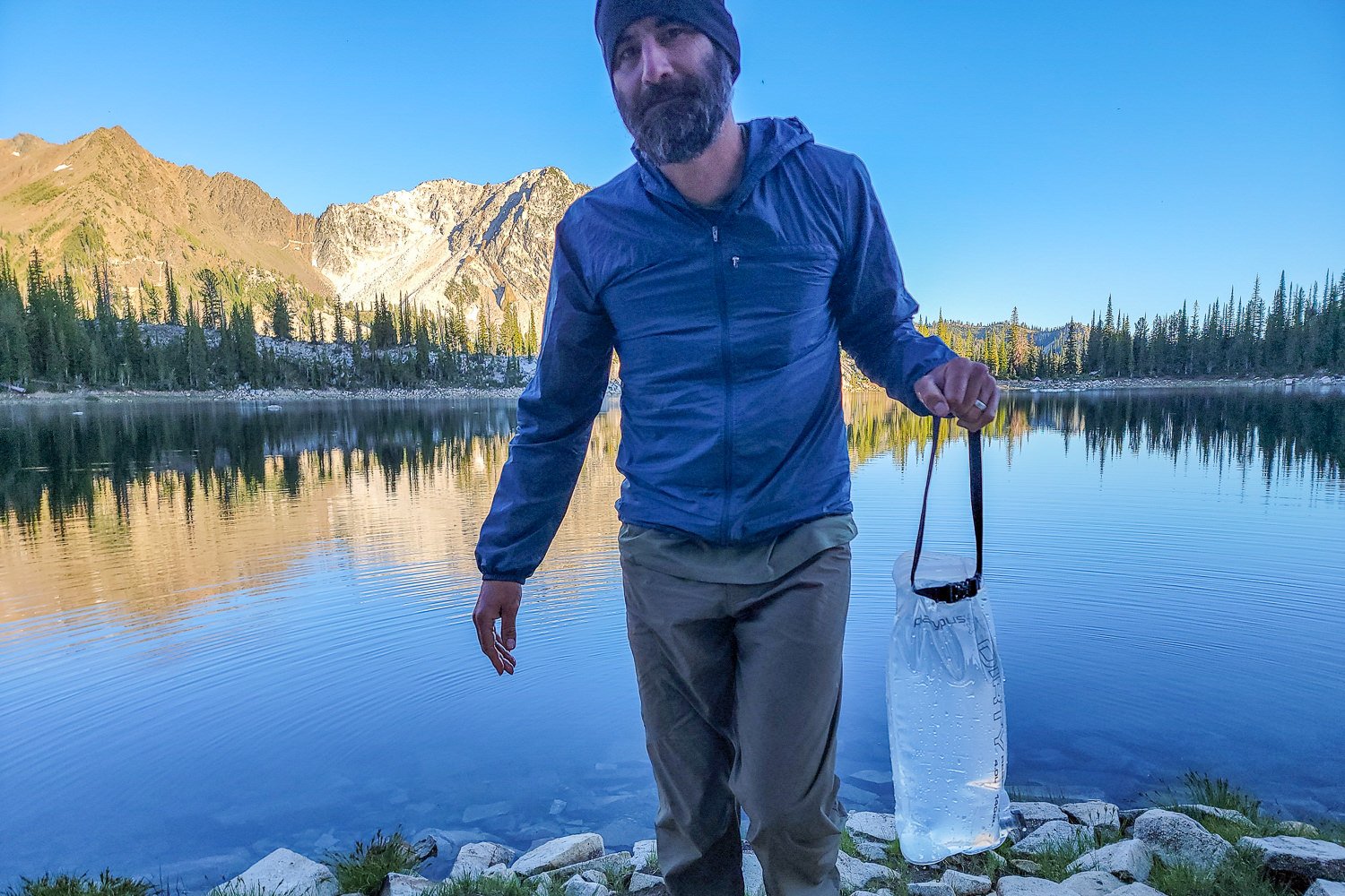 A backpacker carrying the Platypus GravityWorks Water Filter back from a lake
