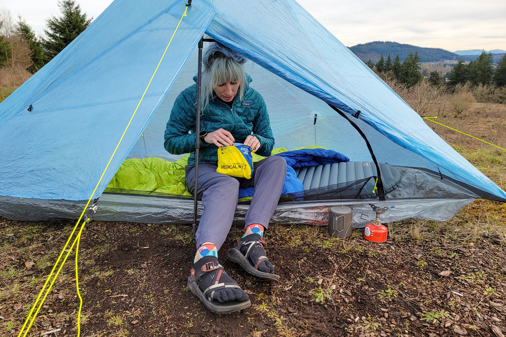 A hiker looking through the AMK Ultralight/Watertight .7 First Aid Kit in a backpacking tent