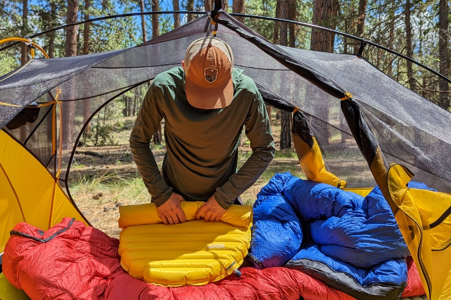 a backpacker packs up their therm-a-rest neoair xlite NXT sleeping pad inside their tent on a sunny morning