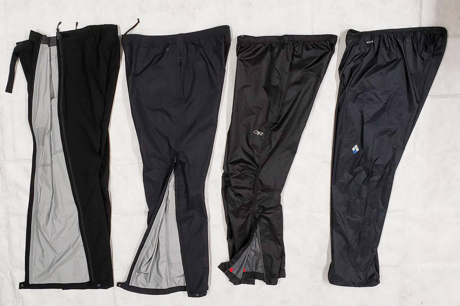 (Left to right) full-zip (Mountain Hardwear Stretch Ozonic Men’s / Women’s), cuff-to-thigh zip (Patagonia Torrentshell 3L Men’s / Women’s), ankle-zip (Outdoor Research Helium Men’s / Women’s) , and no zip pants (Montbell Versalite Men’s / Women’s)