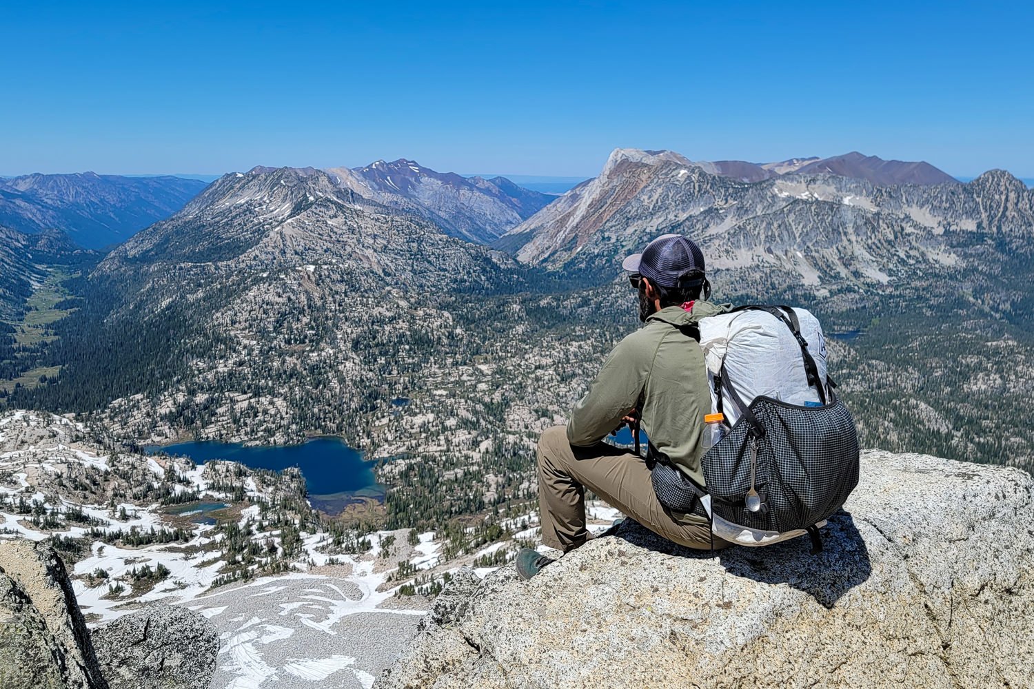 A backpacker wearing the HMG Southwest 40L backpack at the top of a mountain with lakes below