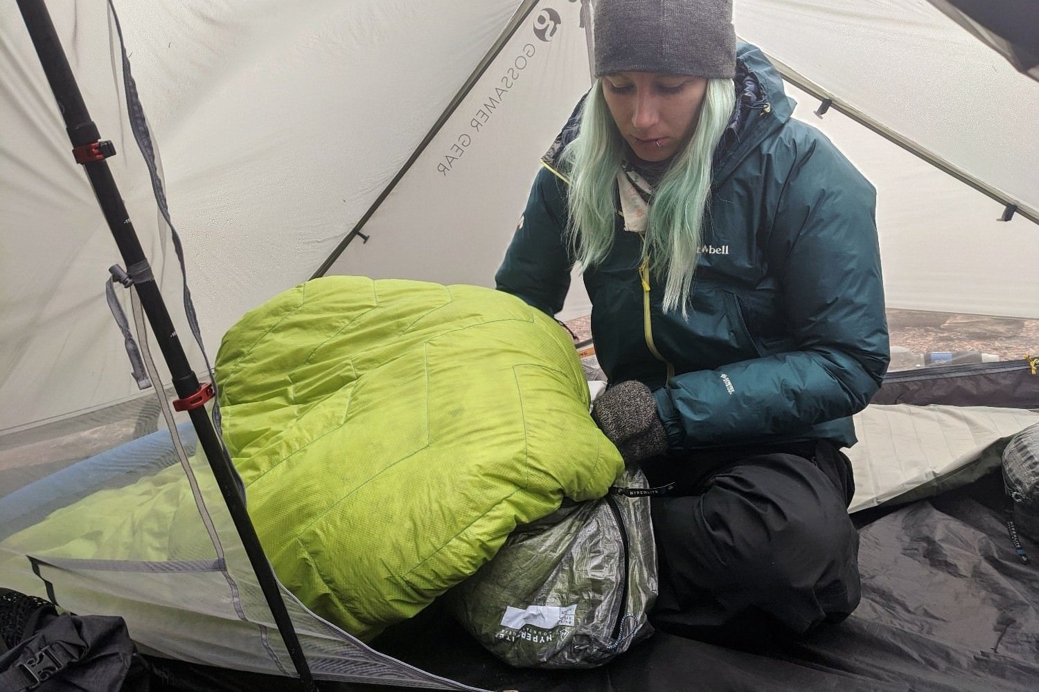 A hiker sitting inside a tent stuffing a quilt into a Hyperlite Mountain Gear Stuff Pod