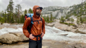 A backpacker wearing an orange Outdoor Research Helium rain jacket in Yosemite National Park