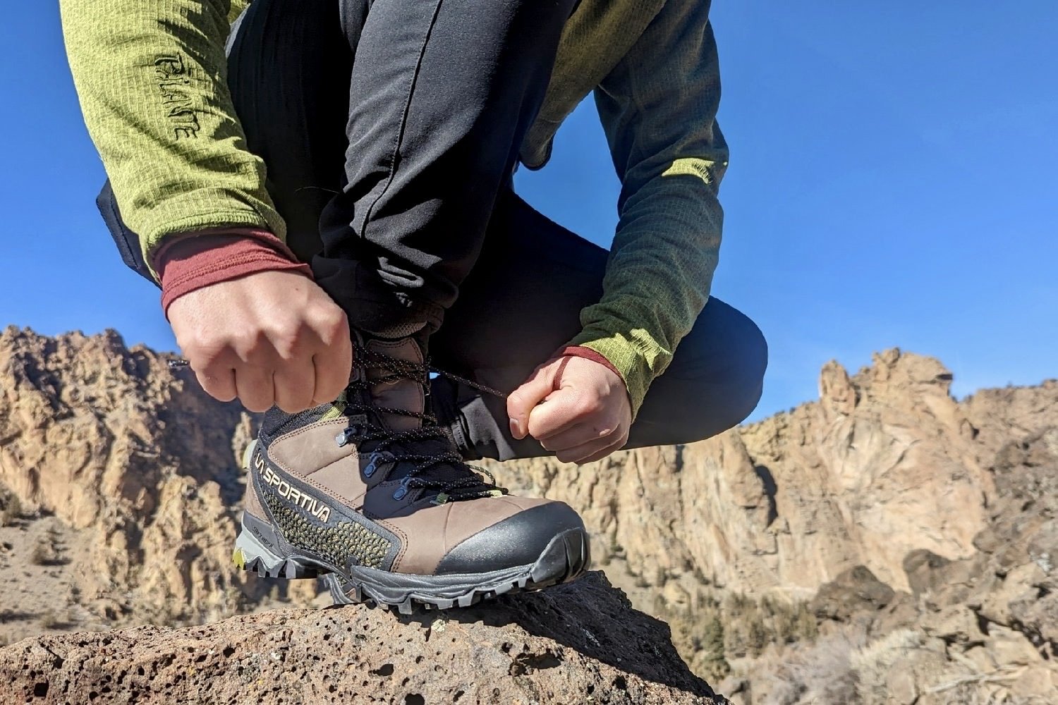 A hiker tying the shoelaces of the la sportiva nucleo boots