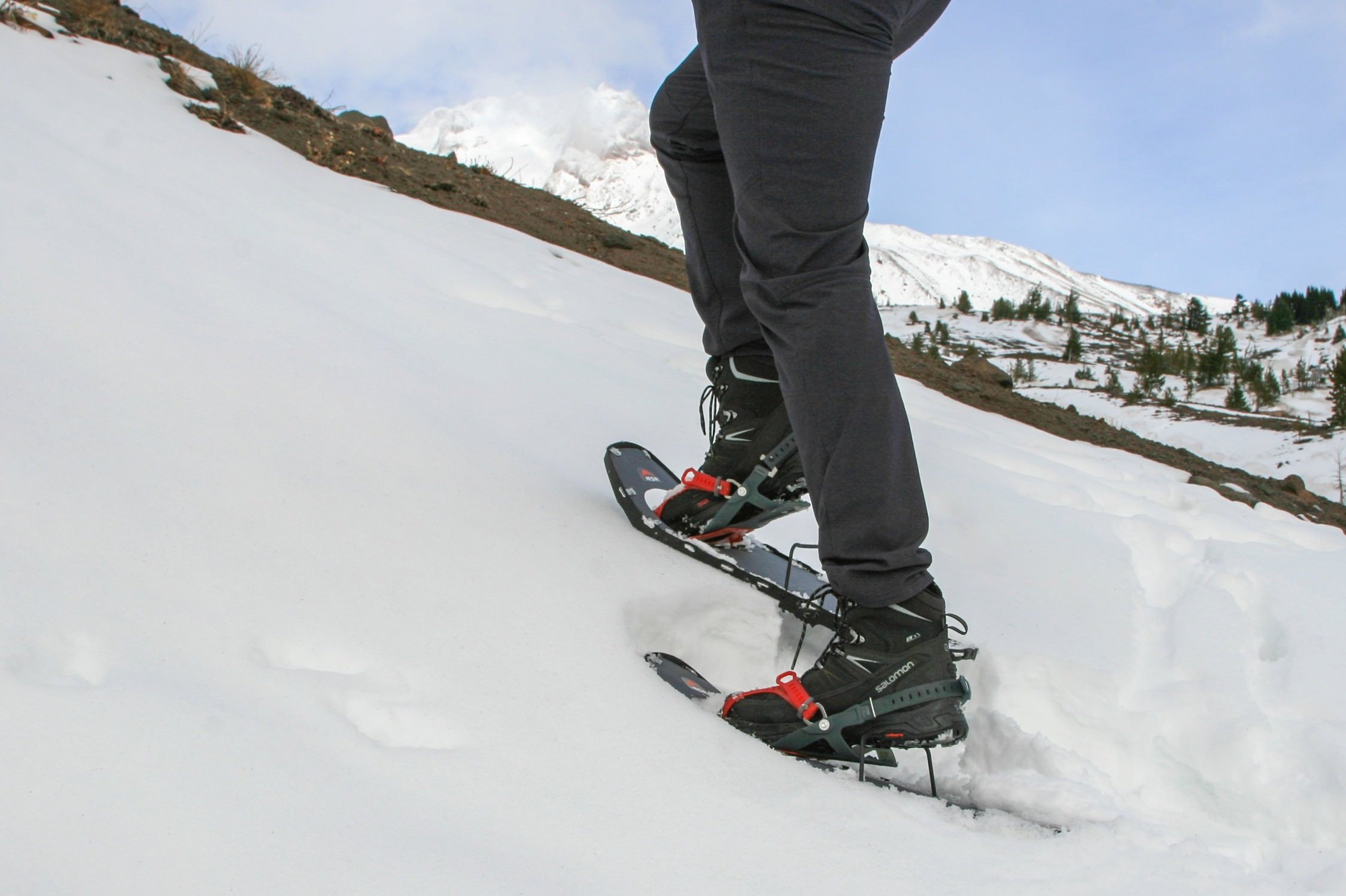 A hiker wearing Salomon X Ultra Mid Winter Boots with MSR Lightning Ascent Snowshoes going uphill