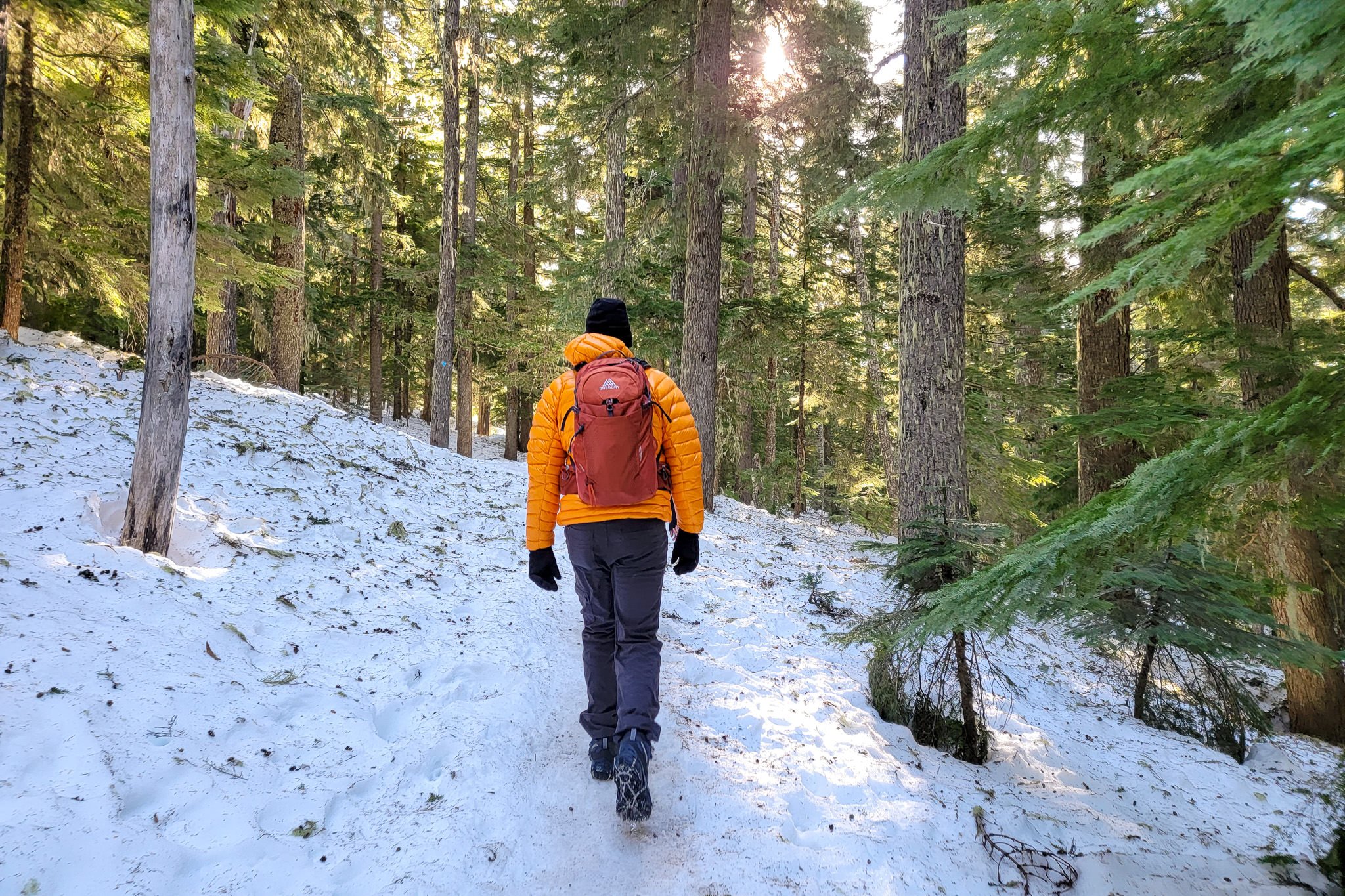 Back view of a hiker walking down a snowy trail in the Snowline Chainsen Trail Light traction devices
