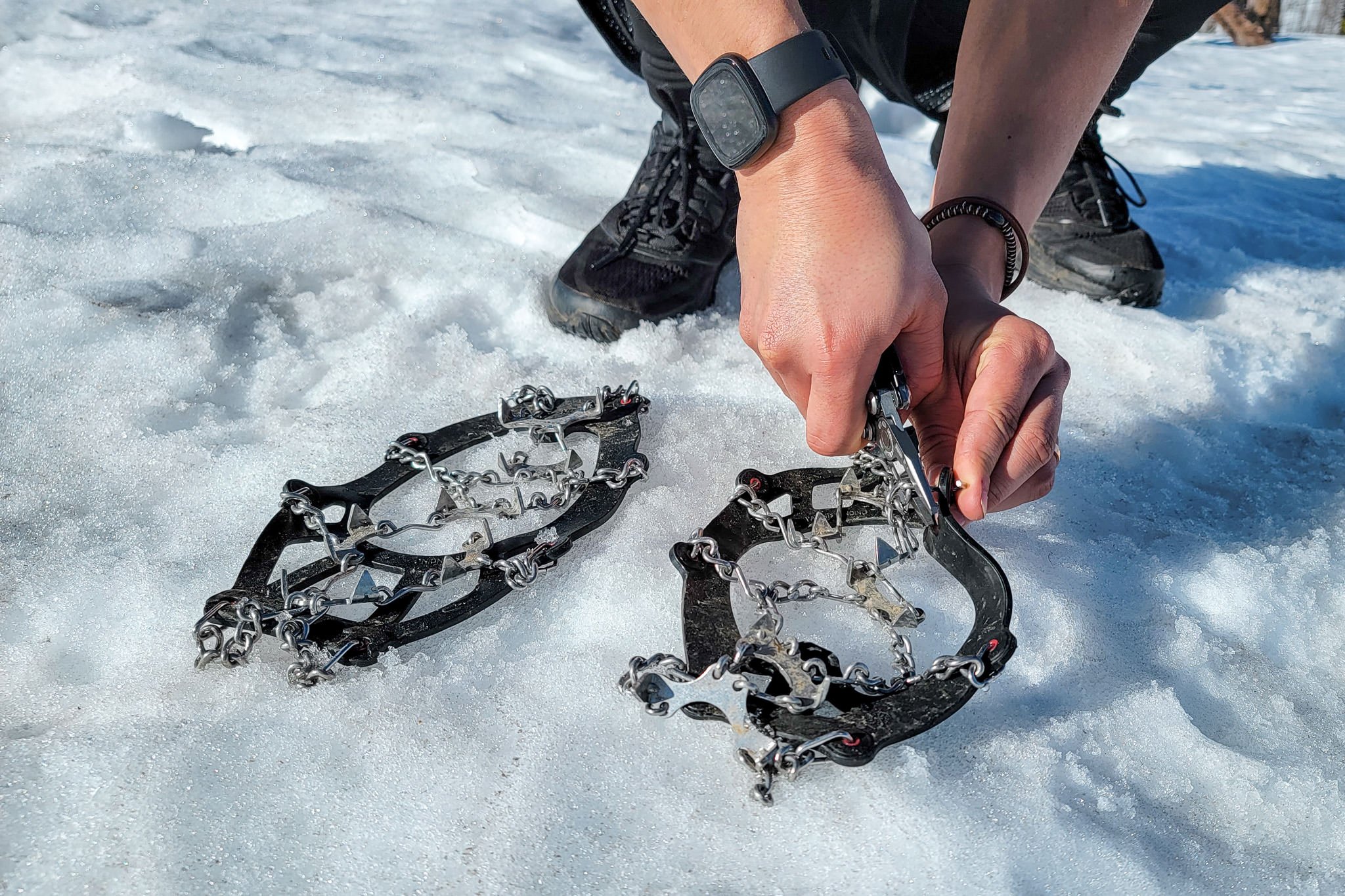 Closeup of a hiker fixing a link on the Kahtoola MICROspikes with a pair of pliers