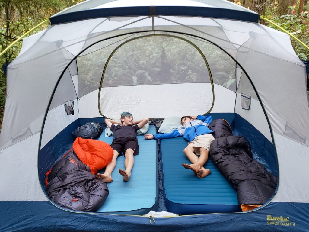 Two kids relaxing on the NEMO Roamer XL Wide & Therm-a-Rest MondoKing 3D XX Large camping mattresses inside of a camping tent