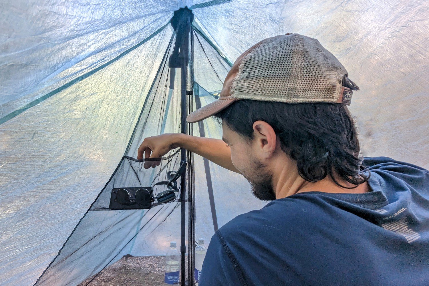 A hiker reaching into the interior pocket of the Durston X-Mid 2 Pro tent for a pair of sunglasses