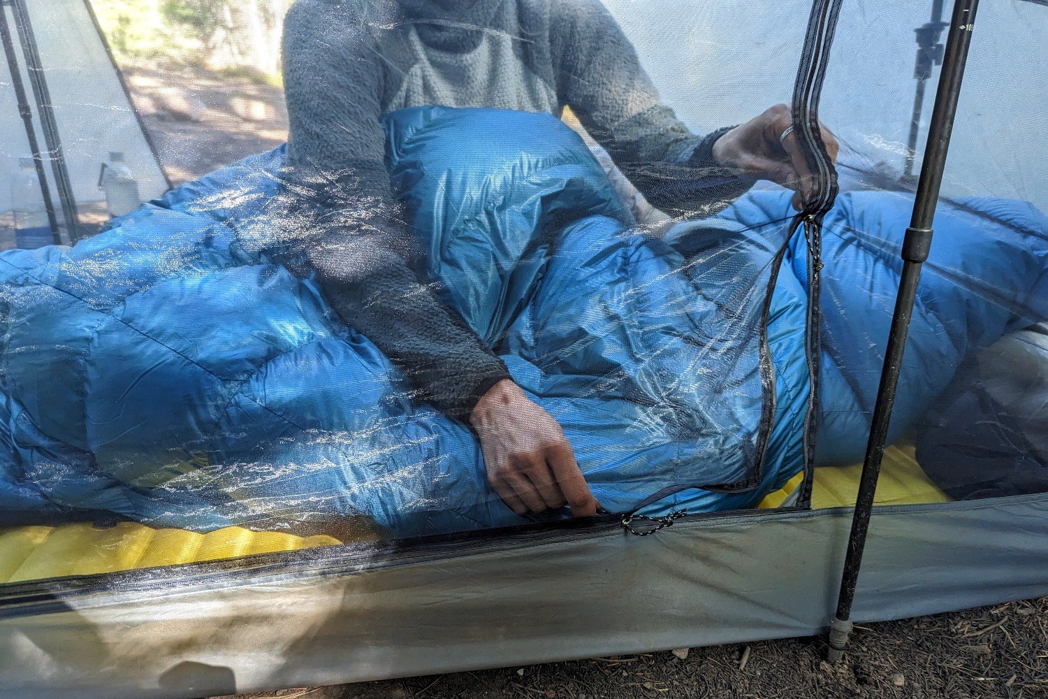 A hiker inside the Durston X-Mid 2 Pro tent opening both of the 90 degree zippers on the door with two hands
