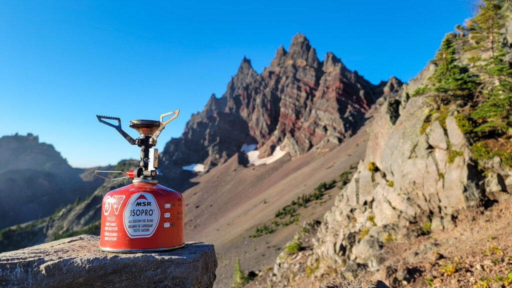 The MSR Pocket Rocket Deluxe backpacking stove in front of a jagged mountain with red bands