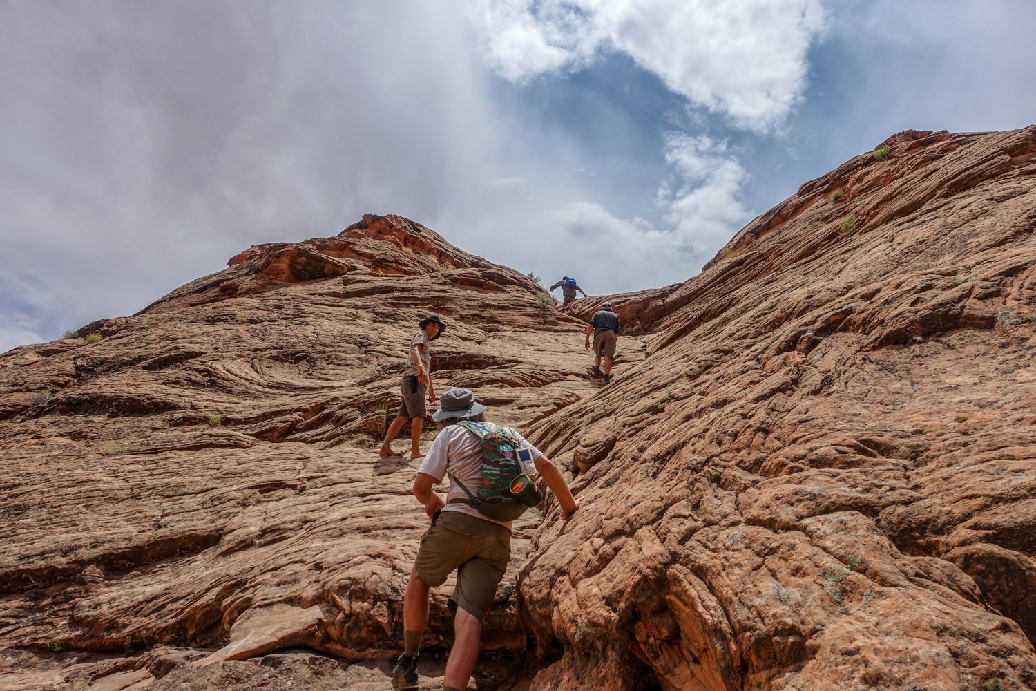 Day hikers scrambling up a rocky face near Coyote Gulch