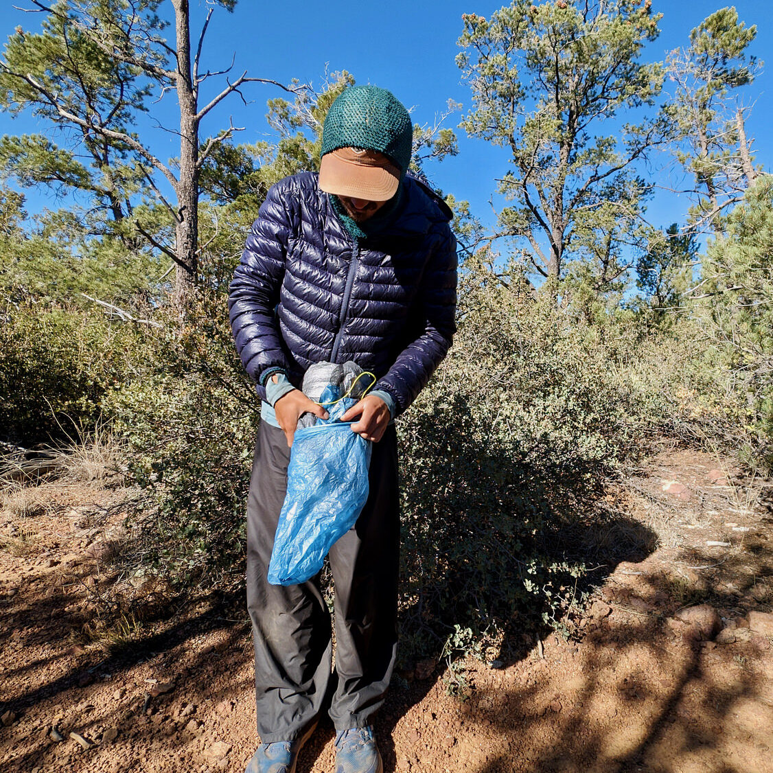 A hiker stuffing the Zpacks Duplex Zip tent into its stuff sack while out in nature