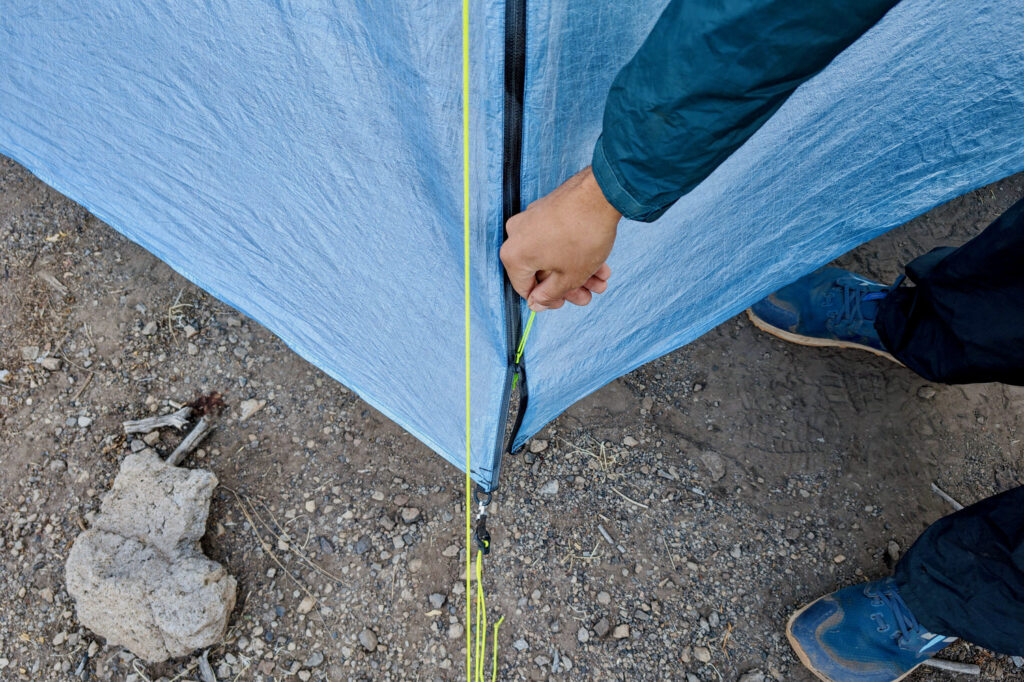 A hand of a backpacker adjusting the zippers on the Zpacks Duplex Zip tent to show how they work