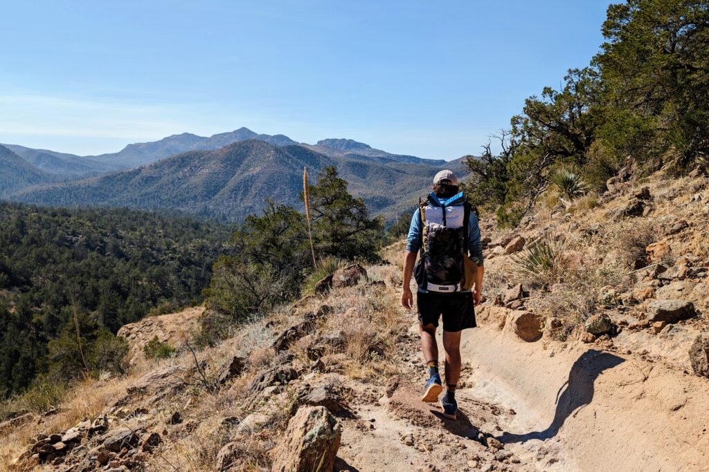 A hiker walking down the trail in Arizona with beautiful views of mountains in the distance