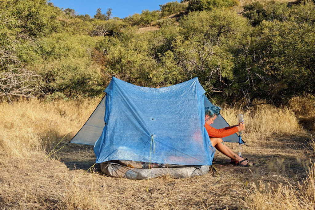 A backpacker opening one door of the Zpacks Duplex Zip tent in the Arizona desert