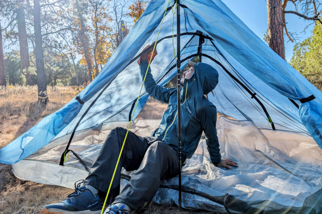 A hiker wiping off the condensation in the inside of the Zpacks Duplex Zip tent from the inside with a small pack towel