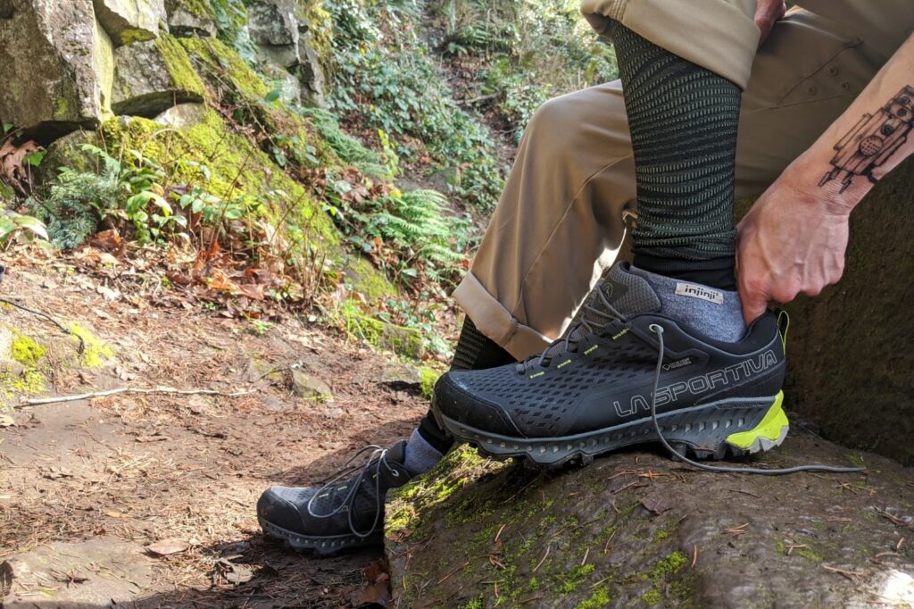 A hiker checking the fit of the La Sportiva Spire GTX hiking shoes by inserting a finger behind his heel