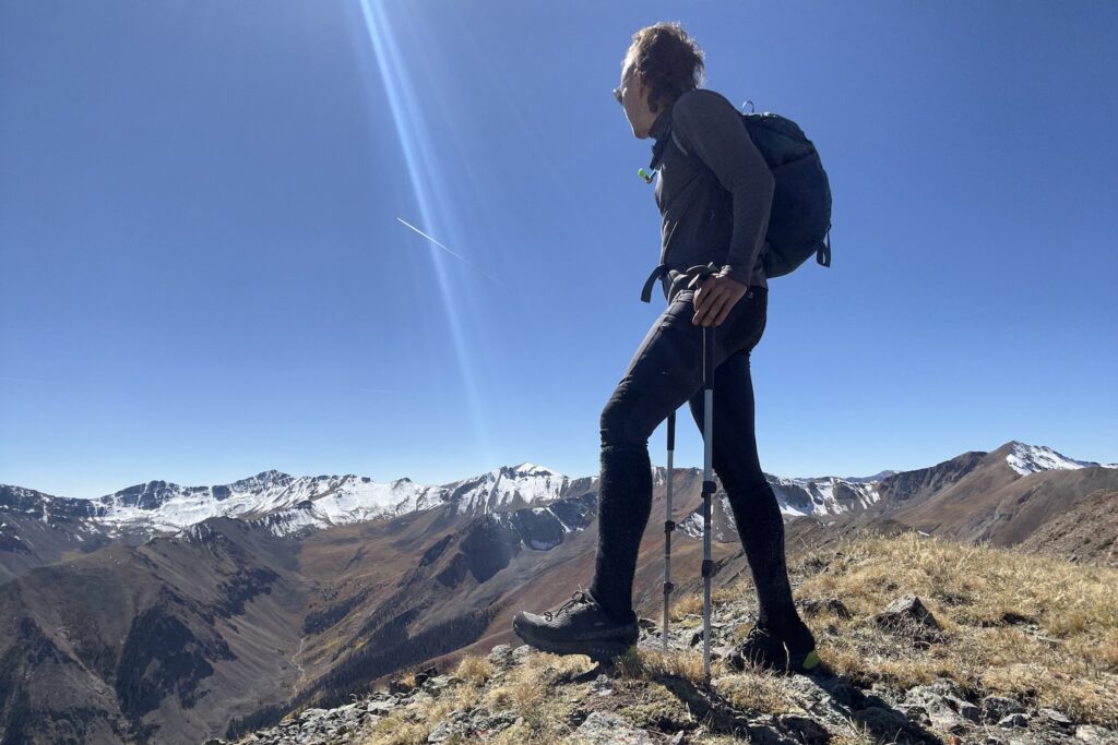 A full-body view of a hiker wearing the men's La Sportiva Spire GTX hiking shoes on a mountain ridge in Colorado