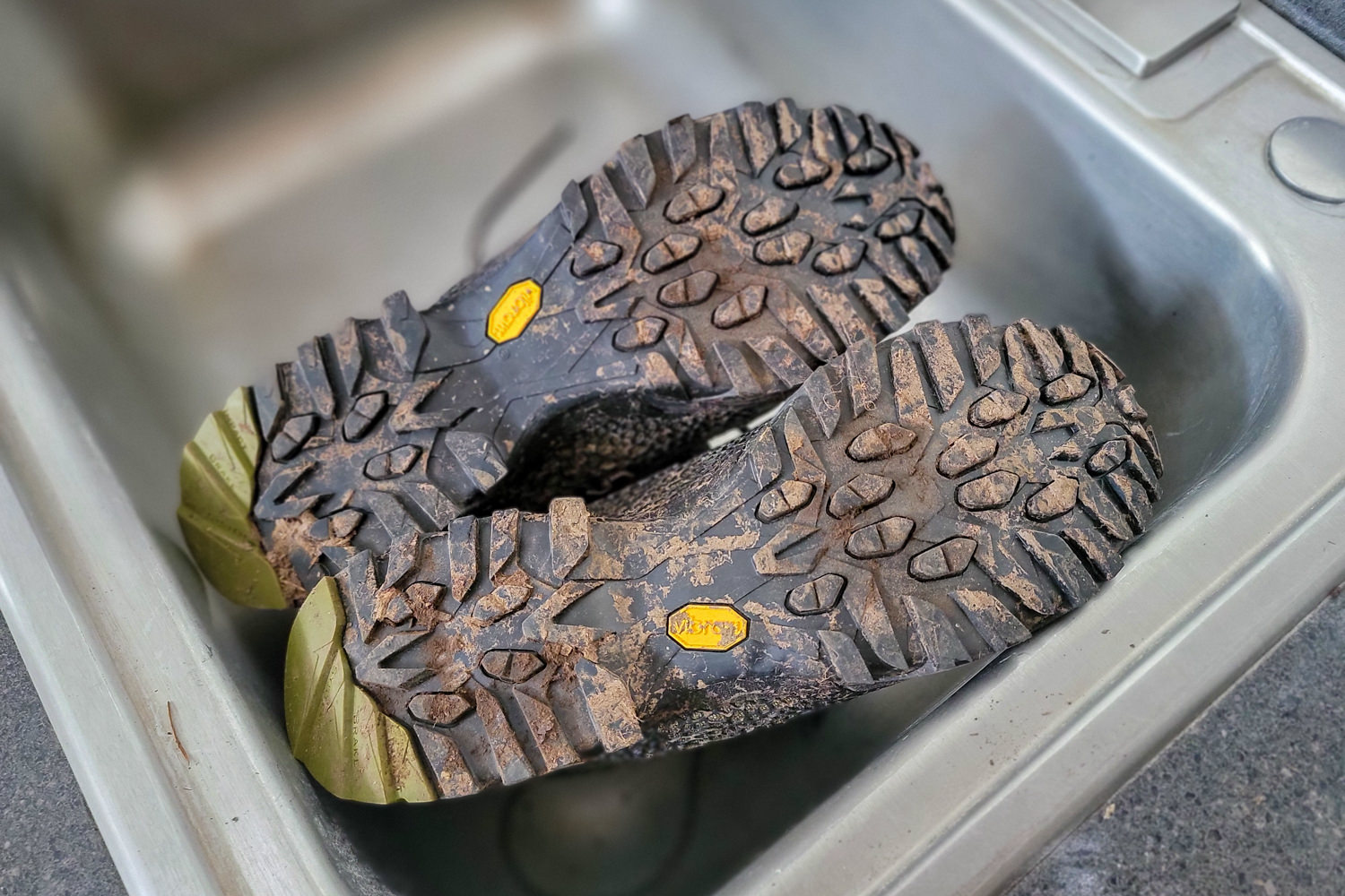 Closeup of the dirty soles of the La Sportiva Nucleo High II GTX hiking boots in a sink