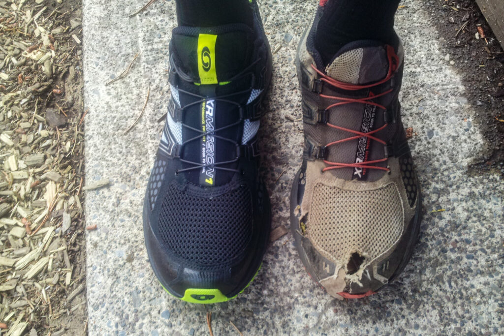 A hiker's feet - one with a brand new Salomon hiking shoe, and one in an old, worn out shoe