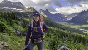 A female backpacker wearing the Eddie Bauer Super Sevens Fleece Pullover in front of jagged mountain peaks in Glacier National Park
