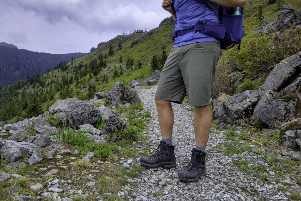 Waist-down view of a hiker standing on a rocky trail in the men's Patagonia Quandary hiking shorts