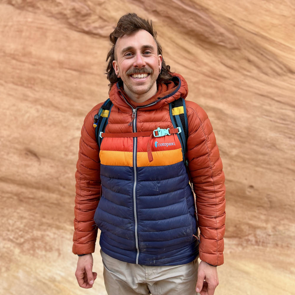 Ian Krammer profile photo with him smiling on a hiking trip with a canyon wall in the background