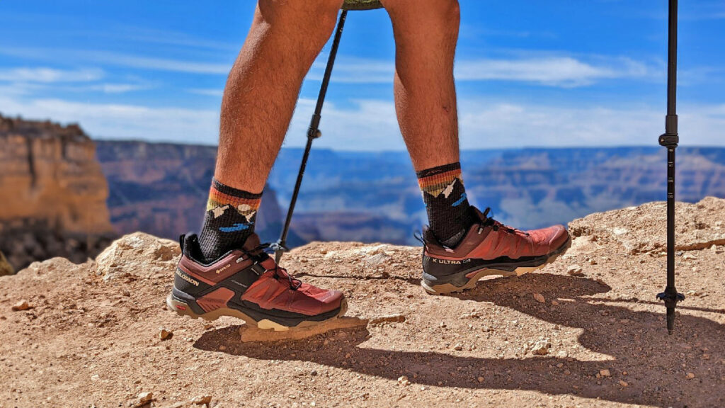 Closeup of a hiker's feet in the Darn Tough Light Hiker Micro Crew socks and Salomon X Ultra shoes on the rim of the Grand Canyon