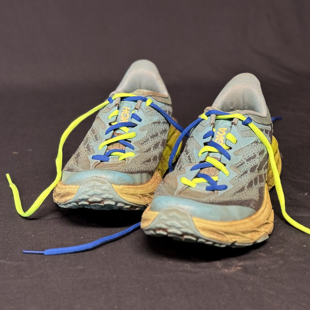 Dual-colored shoelaces demonstrating heel-lock lacing on the women's HOKA Speedgoat trail running shoes
