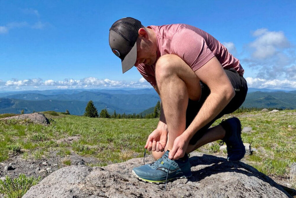 A hiker leaning down to tie his Saucony Peregrine hiking shoe