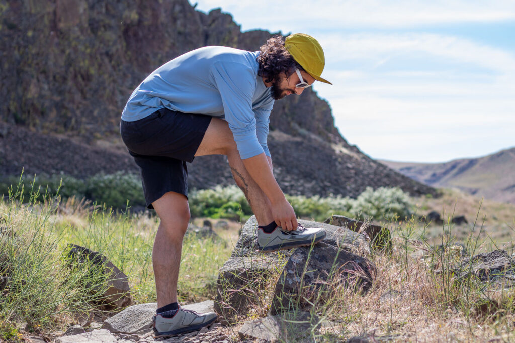 A runner with his foot up on a rock to tie his Altra Lone Peak trail running shoe