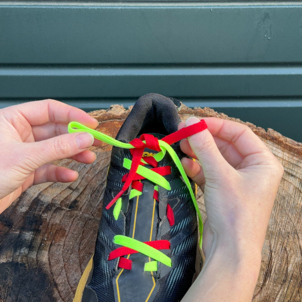 Dual-colored shoelaces demonstrating how to tie and surgeon's knot on the women's HOKA Speedgoat trail running shoes