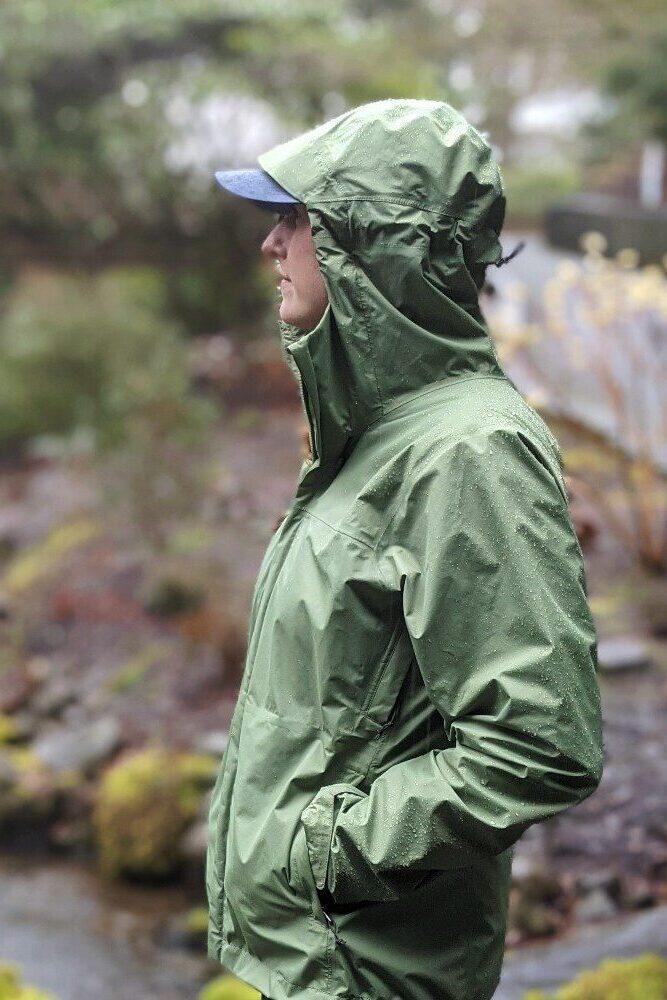 A hiker wearing a green Patagonia Torrentshell 3L rain jacket