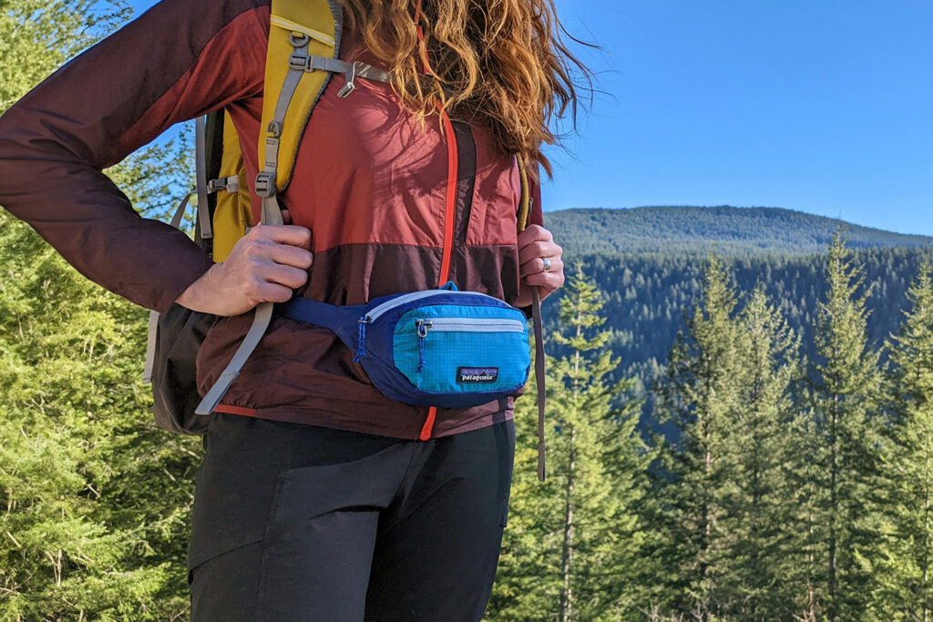 Closeup of a female hiker wearing the Patagonia Black Hole Mini fanny pack with a backpack