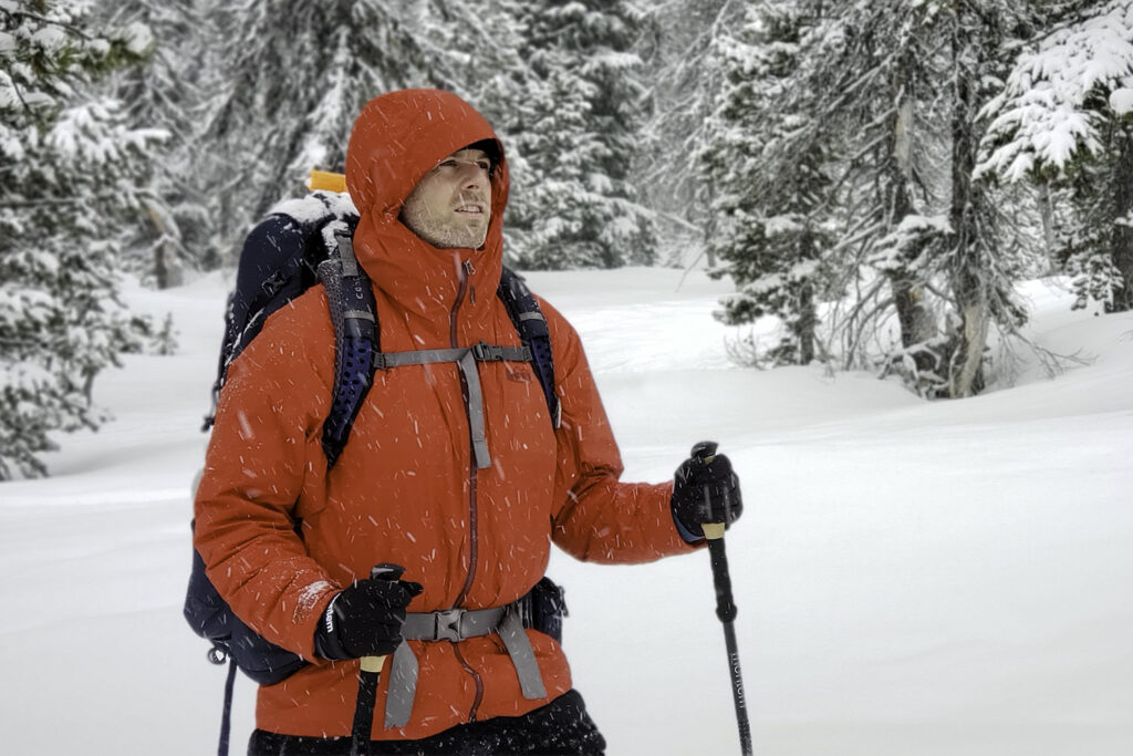 A man with a backpack wearing a red REI Stormhenge winter jacket in a snowy scene