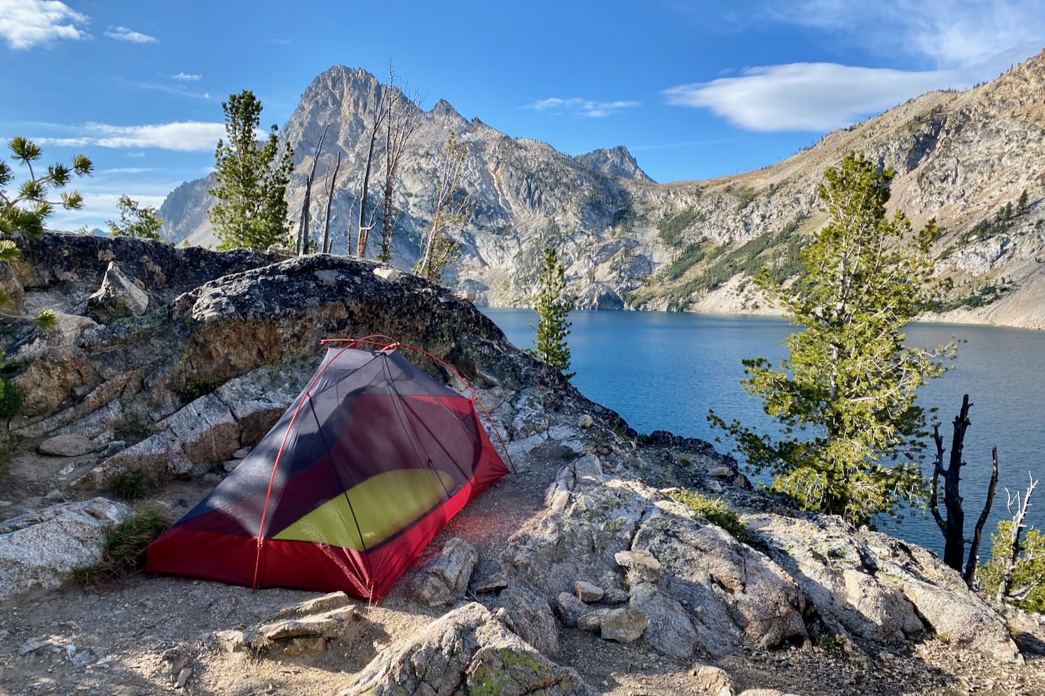 the msr freelite tent set up in a small flat pad between rocks near an alpine lake