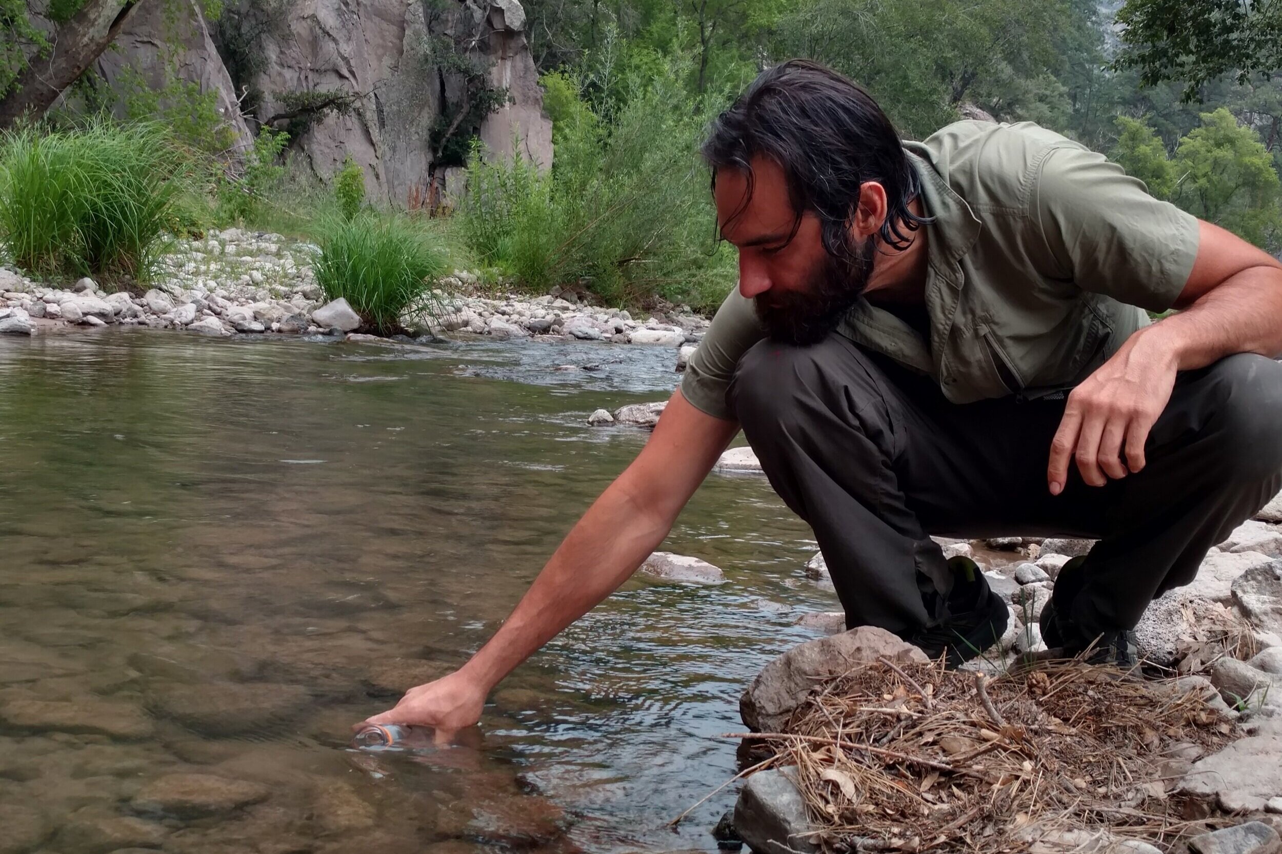 CDT thru-hiker holding his water bottle under the water to fill his water supply.
