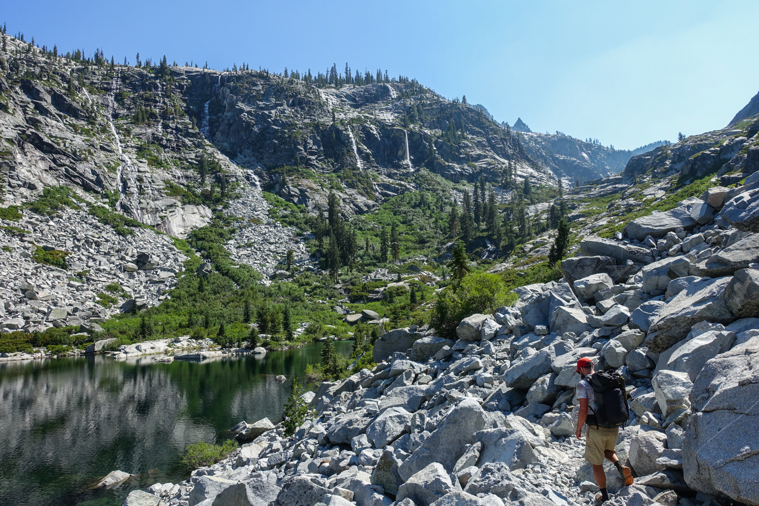 backpacker in the trinity alps along a scree field leading to an alpine lake