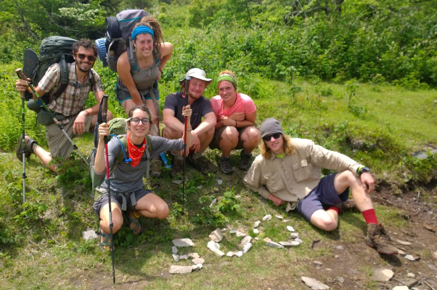 Appalachian Trail thru-hikers gather around the number 500 made with stones on the ground to celebrate hiking 500 miles.