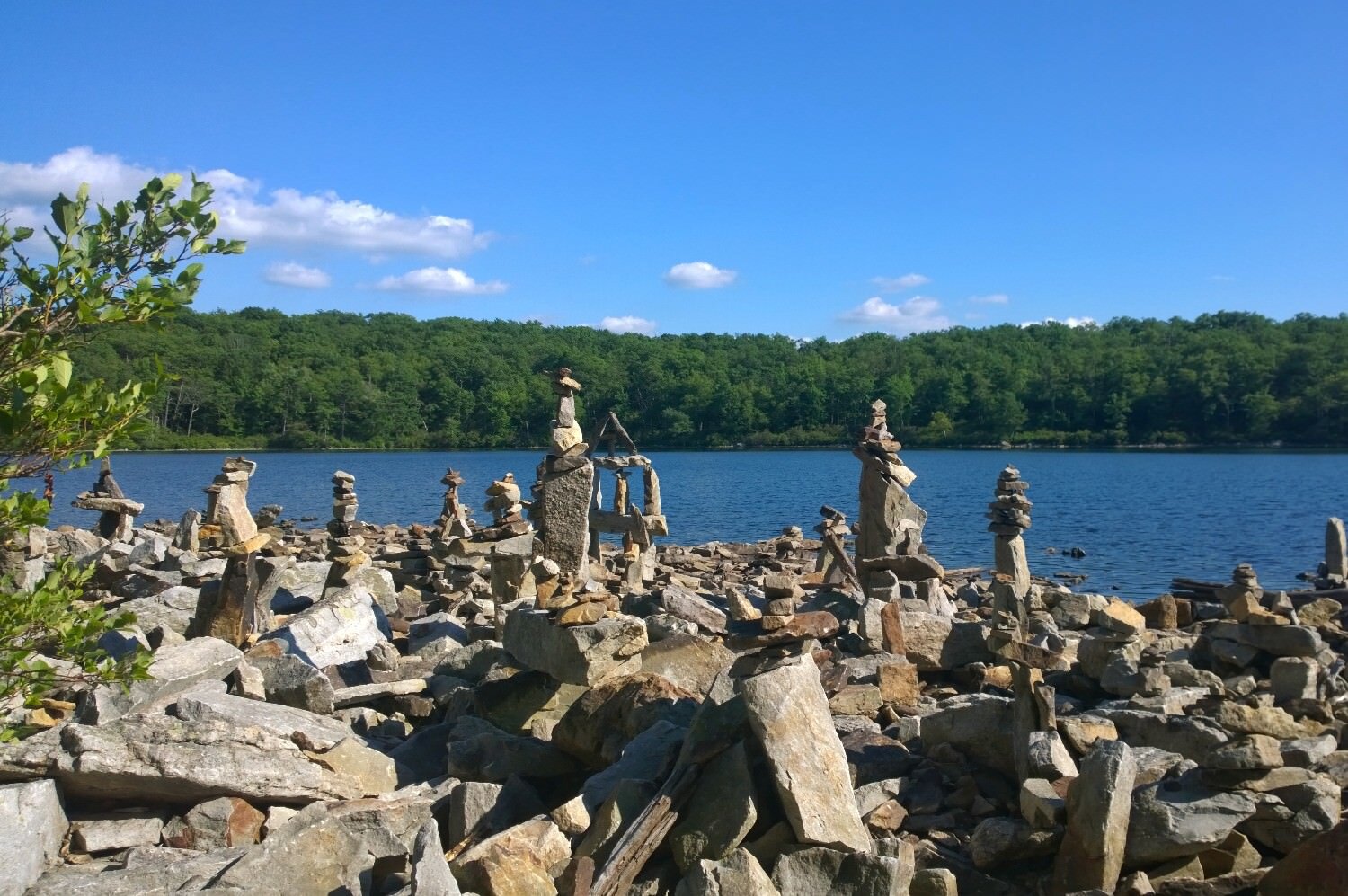 stacked stones alongside a lake on a sunny day