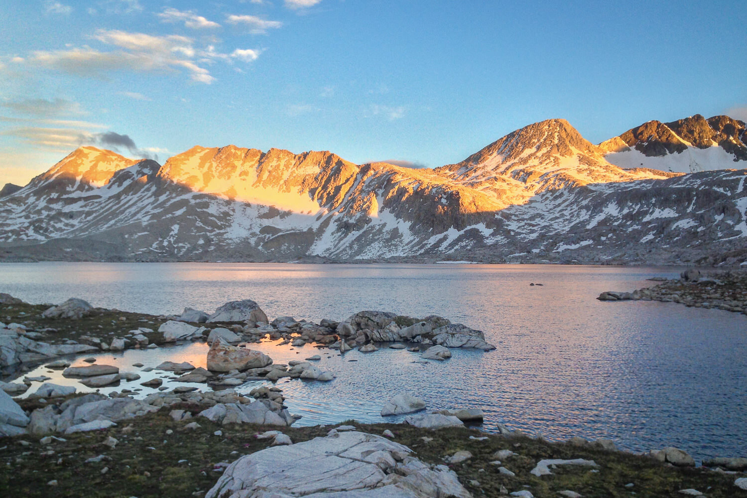 sunrise on alpine lake with rocky mountains surrounding it