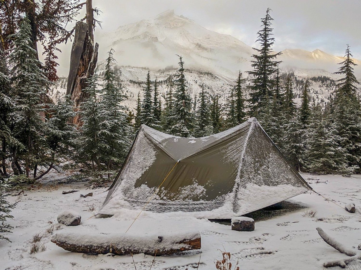 snowfall on a campsite and tent on the three sisters backpacking loop in the fall.