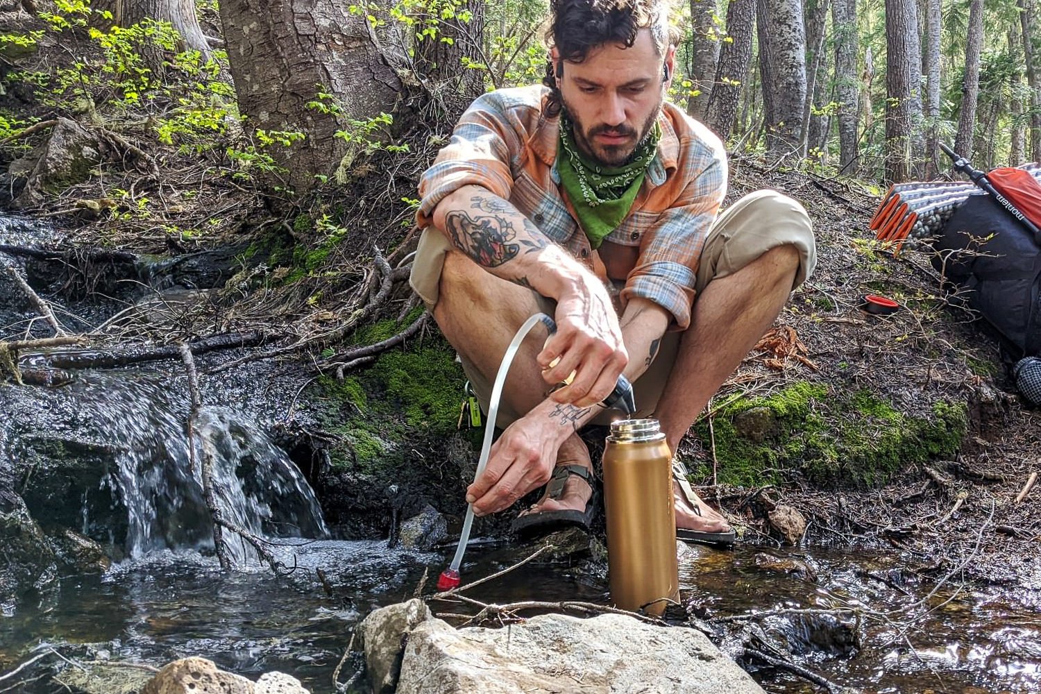 backpacker using a water filter to drink from a stream in the three sisters wilderness