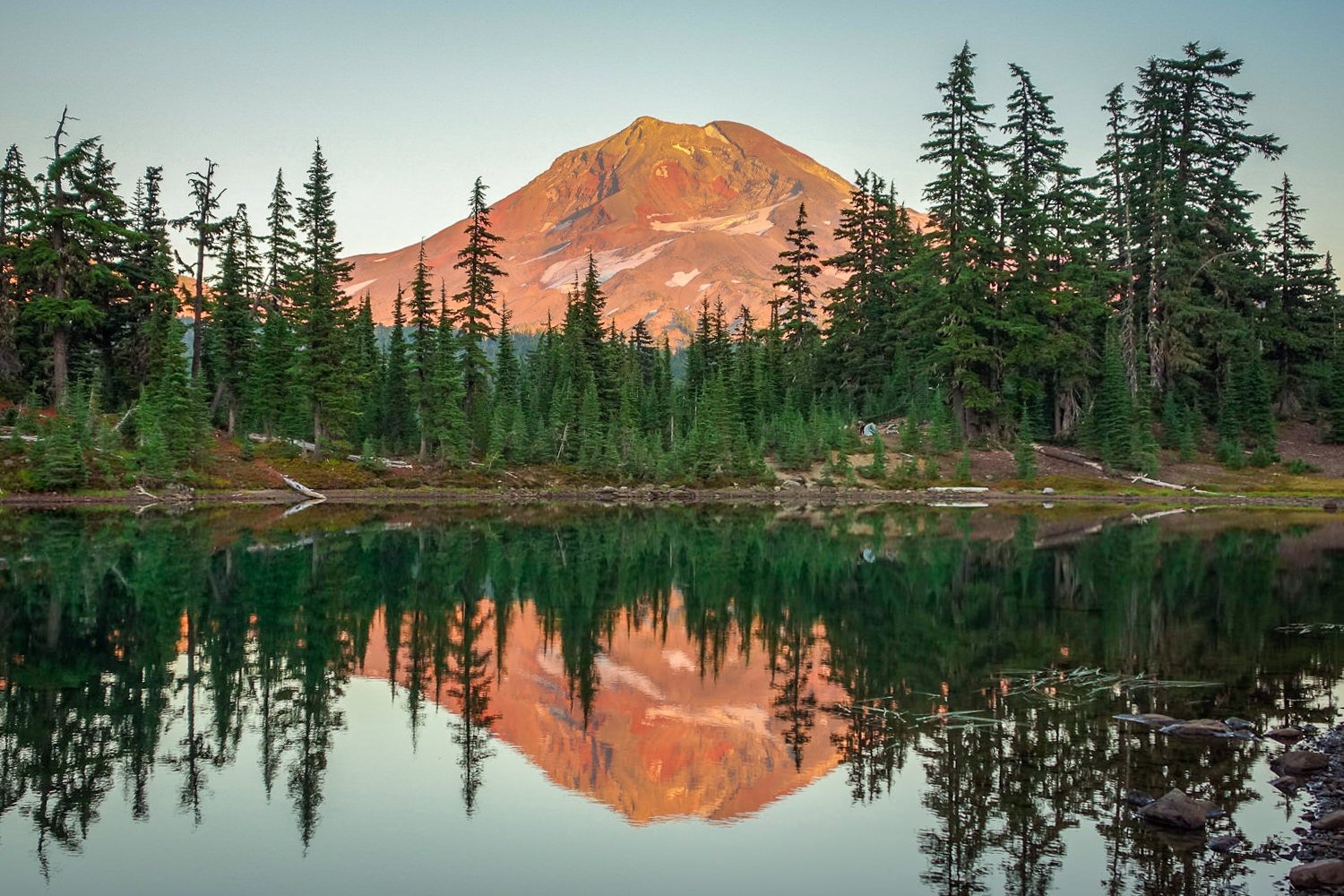 three sisters mountain in alpenglow reflected in a lake
