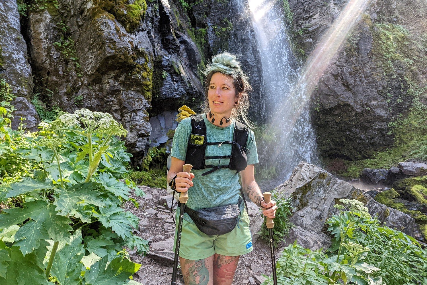 backpacker holding trekking poles next to a small waterfall in the blue mountains