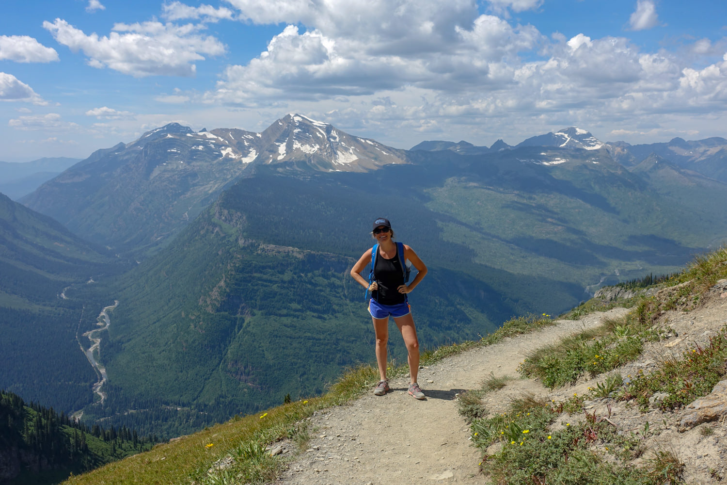 hiker posing with a river and road thousands of feet down in the valley behind them.