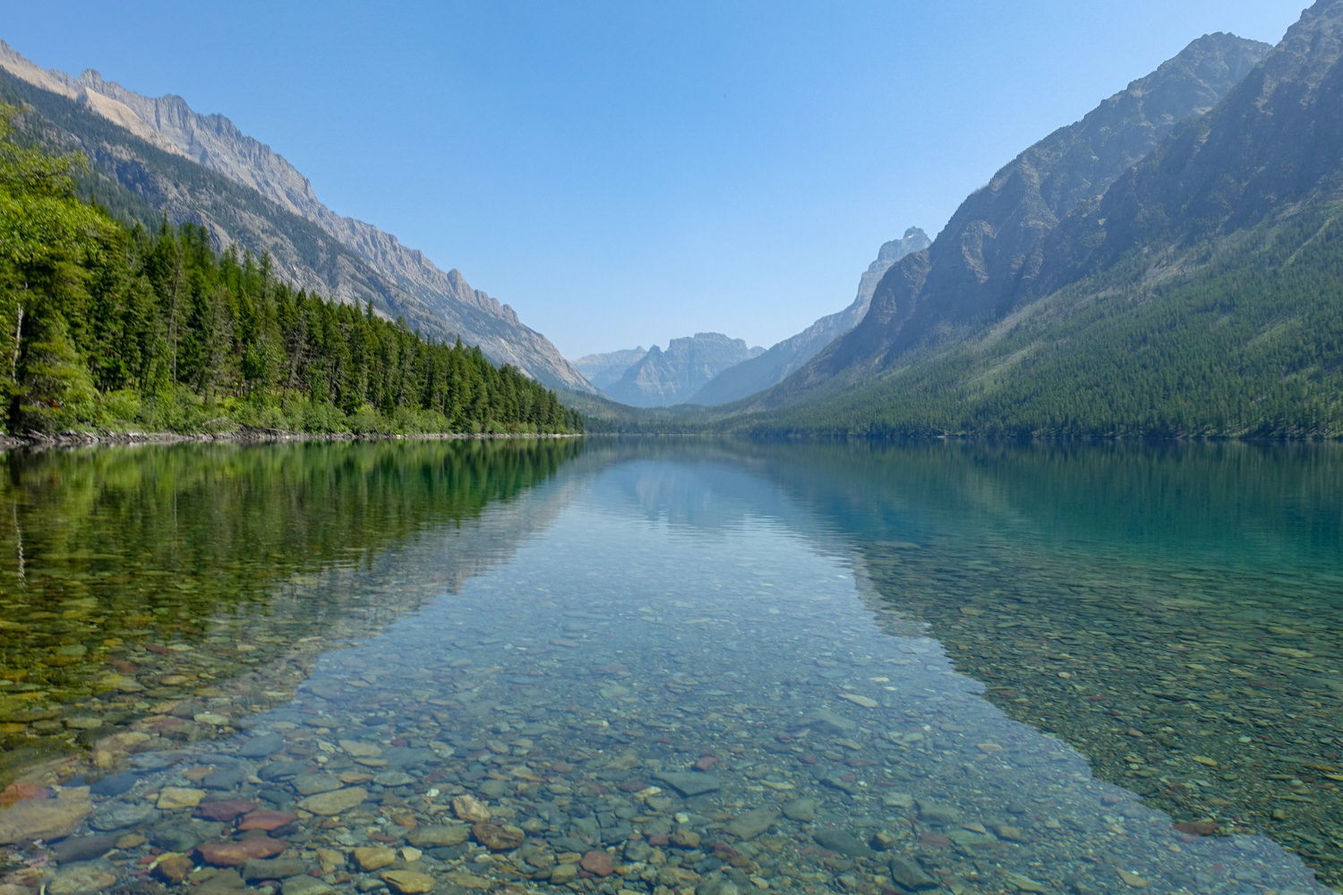 a clear lake with round river rock in glacier national park