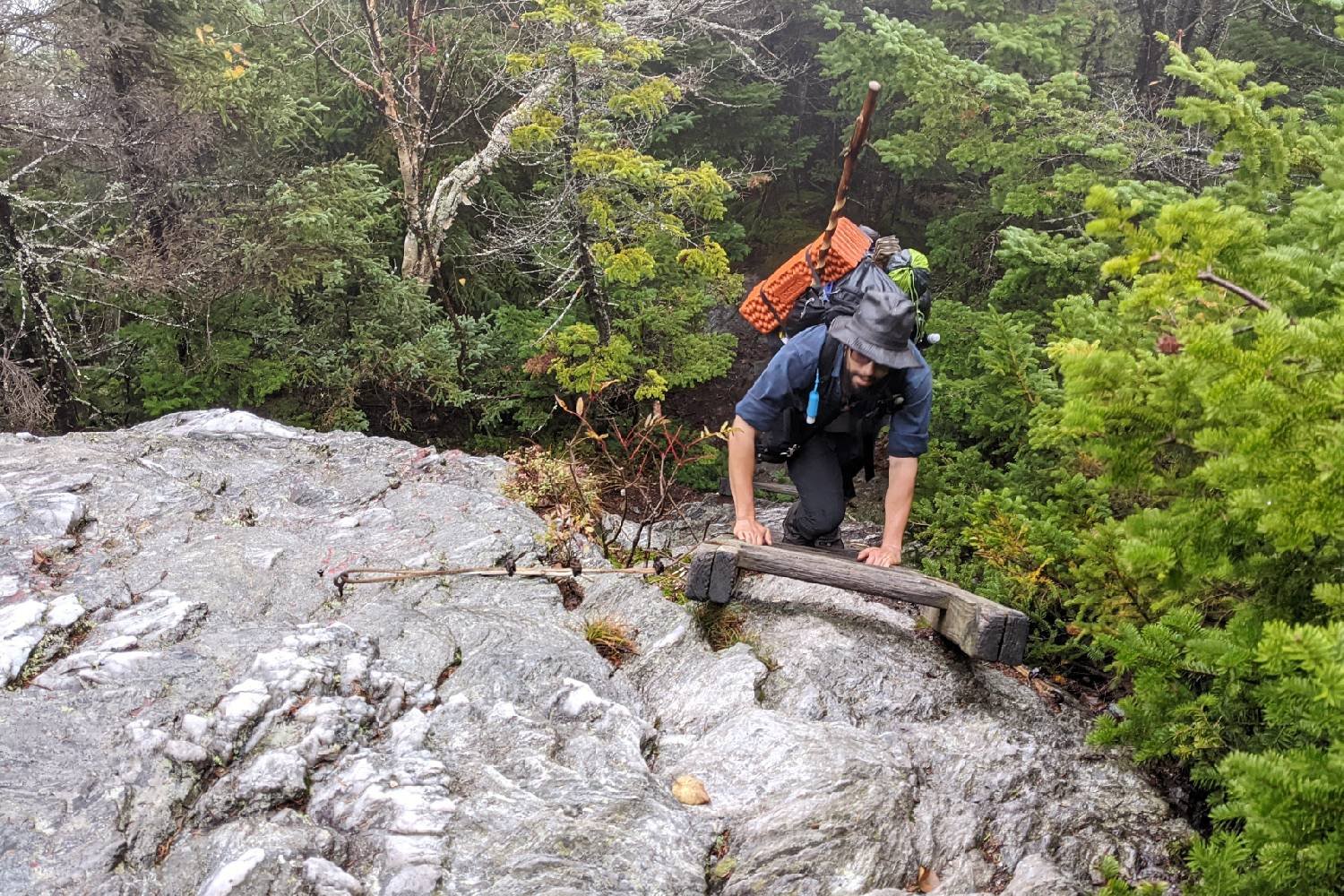 backpacker on the long trail climbing a ladder to get over a steep rock.