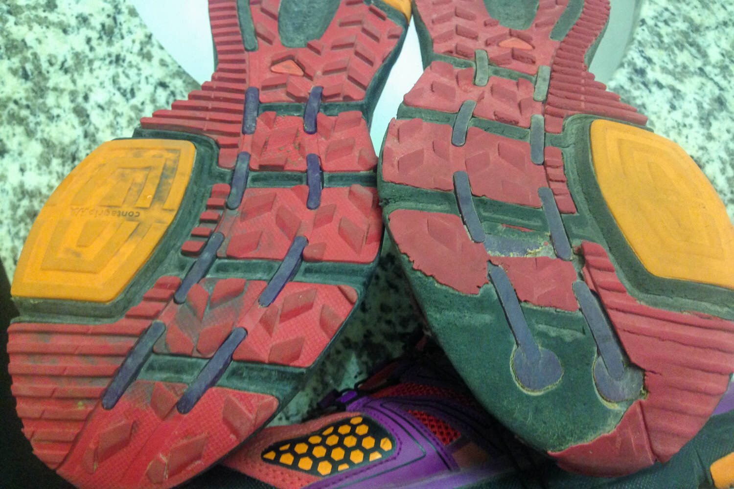 photo of the soles of a trail shoes showing asymmetrical wear and tear on the rubber